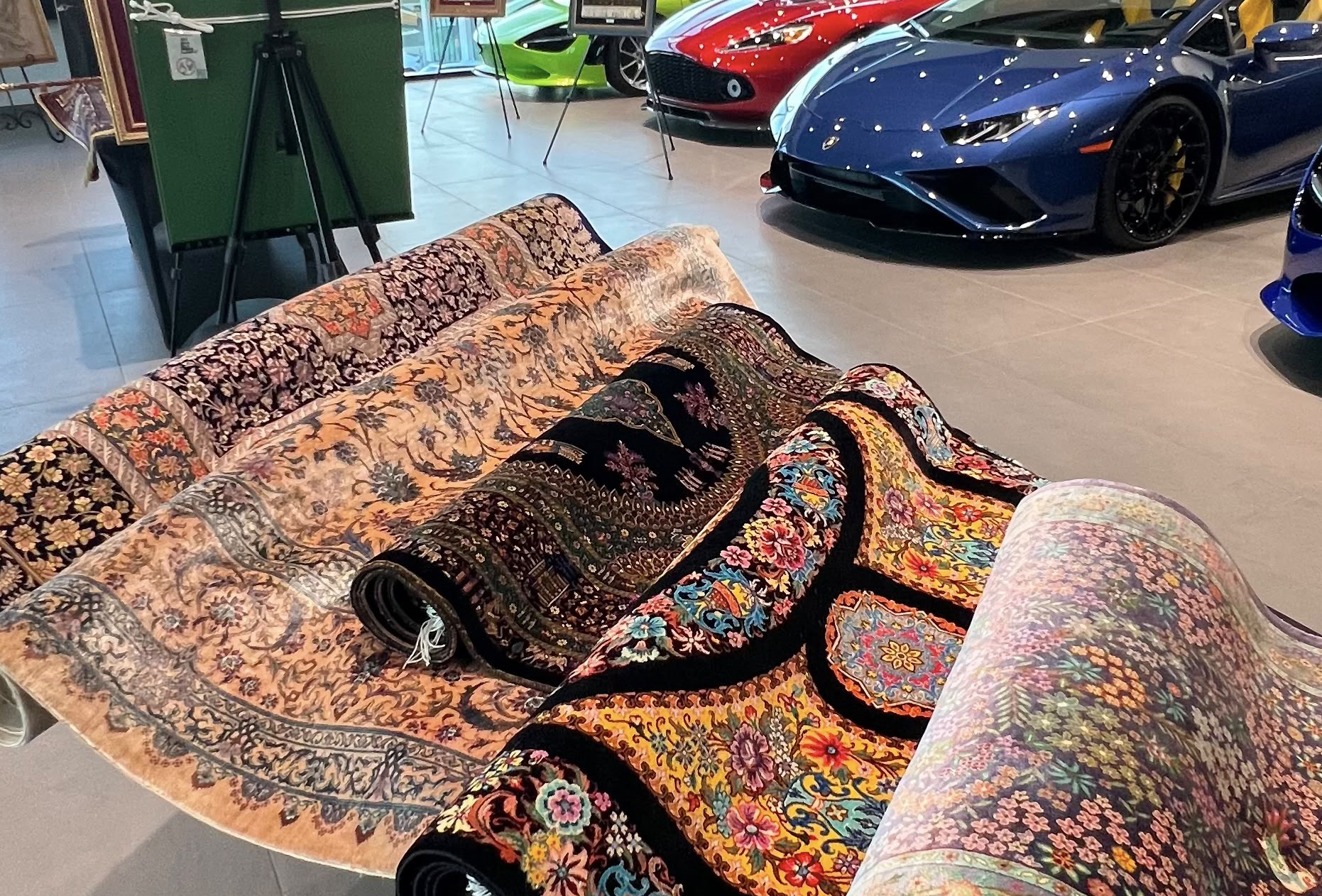 Rugs displayed alongside supercars